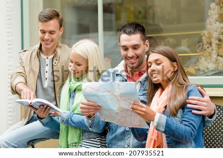 travel, vacation and friendship concept - group of smiling friends with city guide and map exploring town