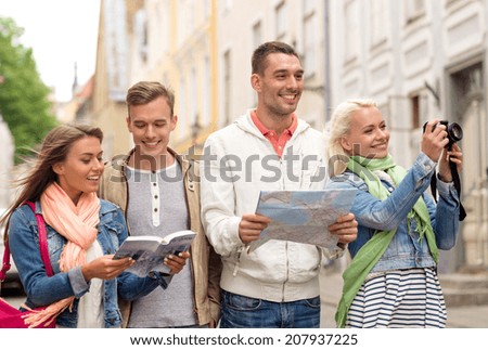 travel, vacation, technology and friendship concept - group of smiling friends with city guide, photocamera and map exploring city