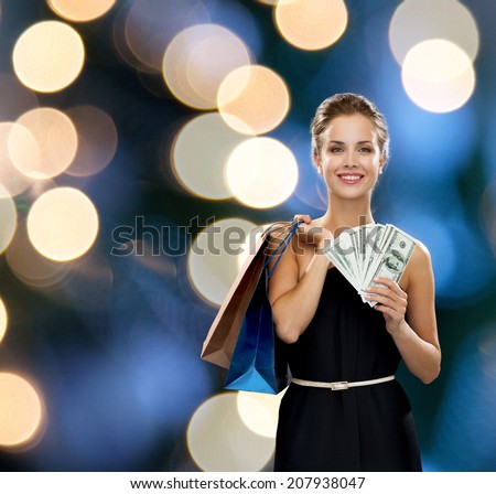 shopping, sale, gifts, money and holidays concept - smiling woman in dress with shopping bags and money over black background