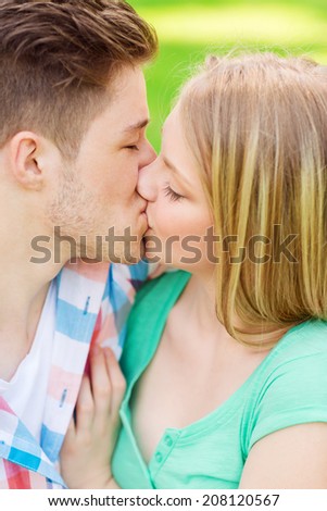 holidays, vacation, love and friendship concept - smiling couple kissing and hugging in park