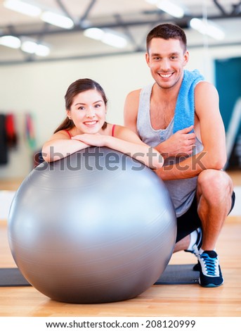 fitness, sport, training, gym and lifestyle concept - two smiling people with fitness ball in the gym