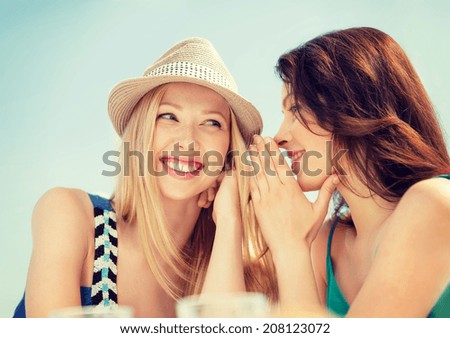 summer holidays and vacation concept - girls gossiping in cafe on the beach