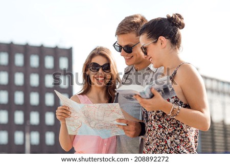 friendship, travel, tourism, vacation and people concept - smiling friends with map and city guide outdoors