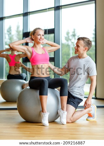 sport, fitness, lifestyle and people concept - smiling man and woman with exercise ball in gym