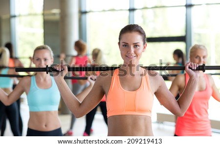 fitness, sport, training, gym and lifestyle concept - group of women with bars in gym