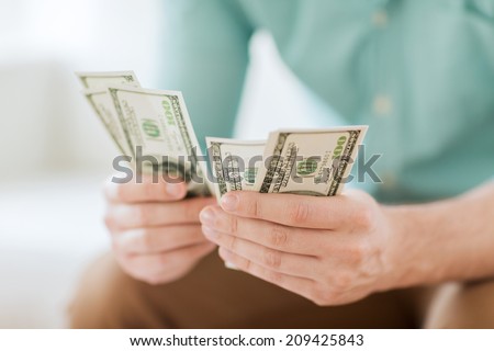 savings, finances, economy and home concept - close up of man counting money at home