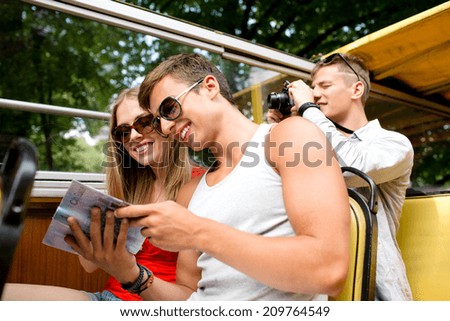 friendship, travel, vacation, summer and people concept - smiling couple looking to city guide book traveling by tour bus