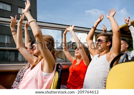 friendship, travel, vacation, summer and people concept - group of smiling friends traveling by tour bus and waving hands