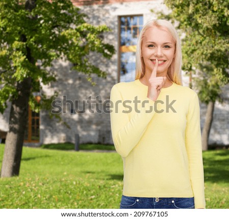 advertisement concept - attractive young woman with finger on her lip