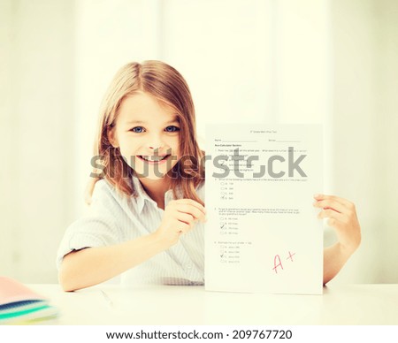 education and school concept - little school girl with test and A grade at school