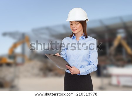 building, developing, construction and architecture concept - smiling businesswoman in white helmet with clipboard making notes