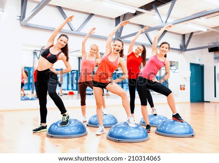 fitness, sport, training and lifestyle concept - group of smiling female doing aerobics with half ball,