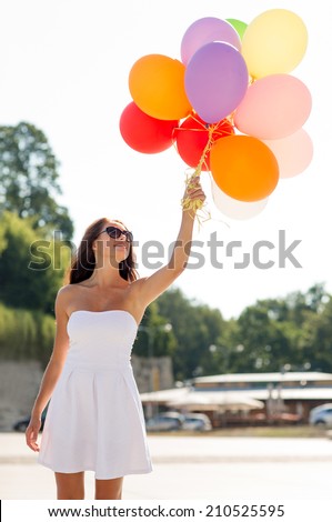 happiness, summer, holidays and people concept - smiling young woman wearing sunglasses with balloons in park