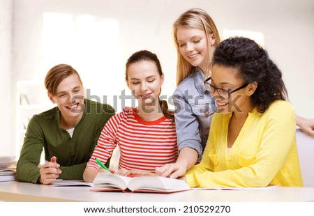 education and school concept - four smiling students with textbooks and books at school