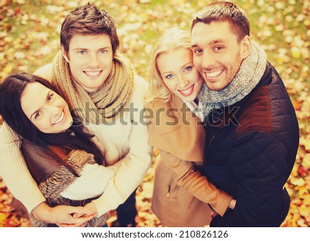 holidays, vacation, happy people concept - group of friends or couples having fun in autumn park
