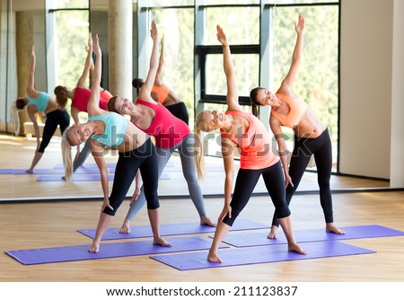 fitness, sport, training and lifestyle concept - group of smiling women stretching in gym