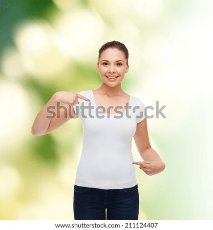 gesture, advertising, ecology and people concept - smiling young woman in blank white t-shirt pointing fingers on herself over green background