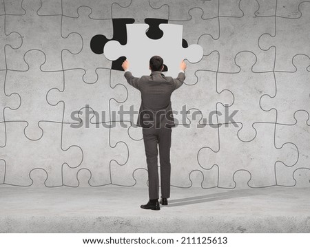 business, development and people concept - businessman in suit setting piece of puzzle to the wall background