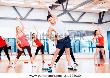 fitness, sport, training, gym and lifestyle concept - group of smiling women stretching in the gym