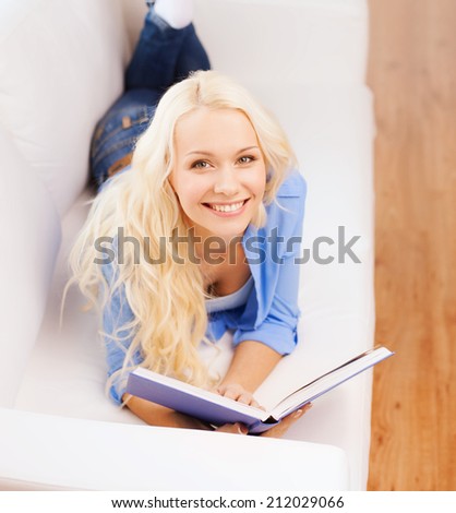 leisure, reading and home concept - smiling middle-aged woman reading book and lying on couch at home