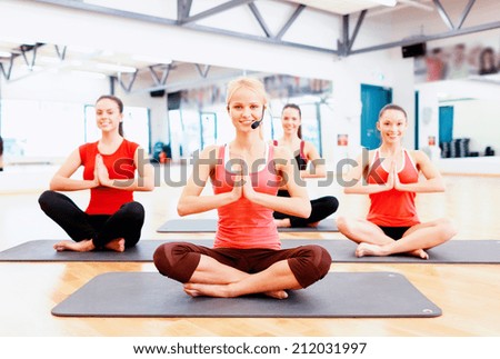 fitness, sport, training, gym and lifestyle concept - group of smiling female with trainer meditating in the gym