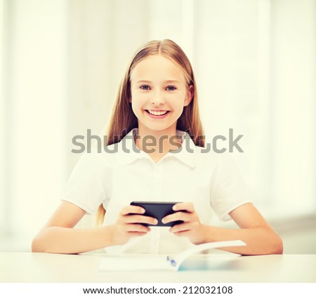 education, school, technology and internet concept - little student girl with smartphone at school