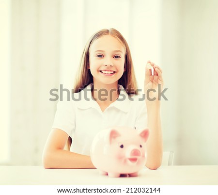 education, school and money saving concept - child putting coins into piggy bank