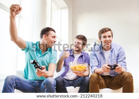 friendship, technology, games and home concept - smiling male friends playing video games at home