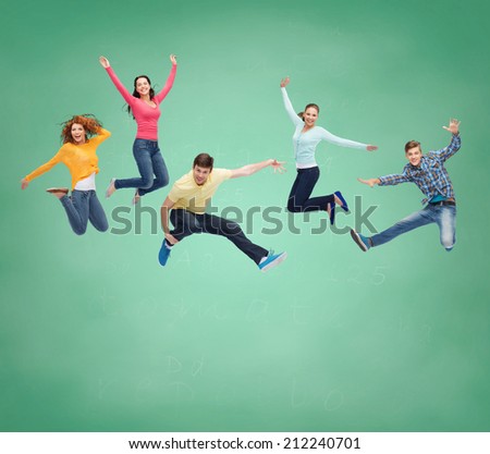 happiness, freedom, friendship, education and people concept - group of smiling teenagers jumping in air over green board background