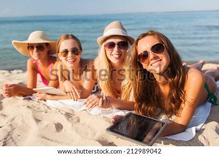 summer vacation, travel, technology and people concept - group of smiling women in sunglasses with tablet pc computers lying on beach