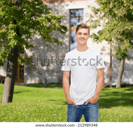 advertising, vacation, education and people concept - smiling young man in blank white t-shirt over campus background