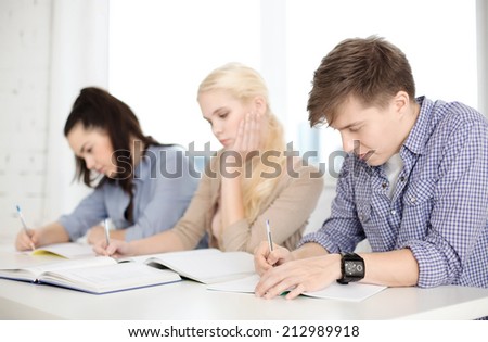 school and education concept - group of tired students with notebooks at school