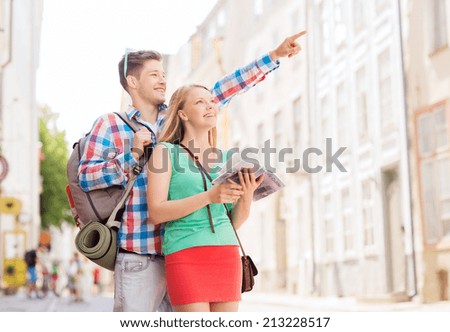 travel, vacation and friendship concept - smiling couple with city guide and backpack in city