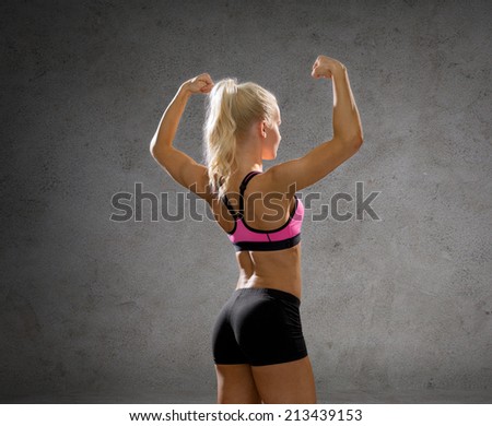 fitness, sport and people concept - smiling athletic woman in sportswear form back over concrete wall background