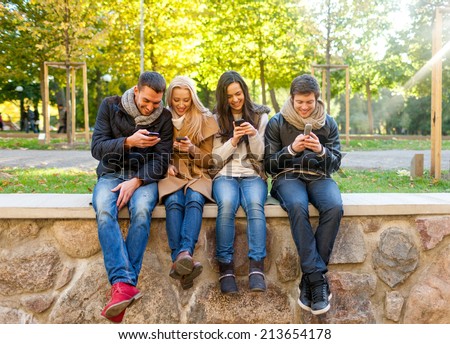 travel, vacation, people, technology and friendship concept - group of smiling friends with smartphones in city park