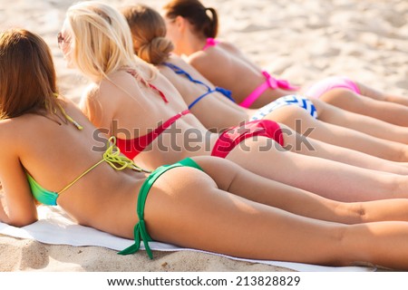 summer vacation, holidays, travel and people concept - close up of young women lying on beach from back