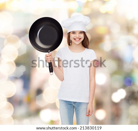 advertising, childhood, cooking and people - smiling girl in white t-shirt and cooking hat holding pan over holidays background