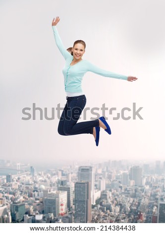 happiness, freedom, movement and people concept - smiling young woman jumping in air over city background