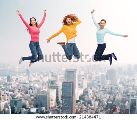 happiness, freedom, friendship, movement and people concept - group of smiling young women  jumping in air over city background