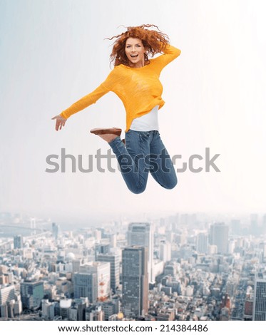 happiness, freedom, movement and people concept - smiling young woman jumping in air over city background