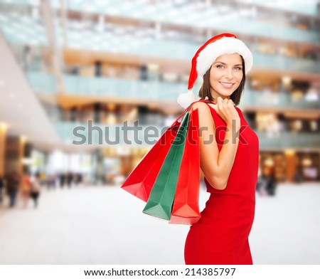 sale, gifts, christmas, holidays and people concept - smiling woman in red dress with shopping bags over shopping center background