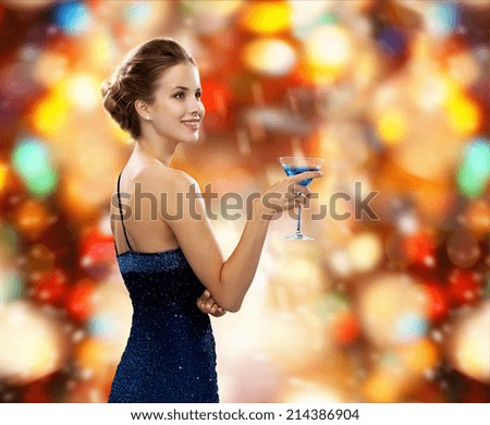 party, drinks, winter holidays, luxury and celebration concept - smiling woman in evening dress holding cocktail over red christmas lights background