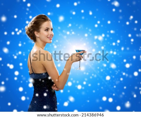 drinks, winter holidays, christmas, luxury and celebration concept - smiling woman in evening dress holding cocktail over black background over blue snowy background