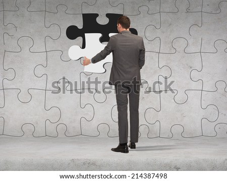 business, development and people concept - businessman in suit setting piece of puzzle to the wall background
