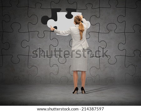 business, development and people concept - businesswoman in suit setting piece of puzzle to the wall background