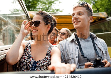 friendship, travel, vacation, summer and people concept - smiling couple with camera traveling by tour bus