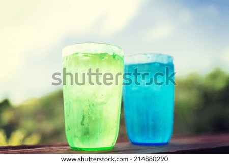 summer, drinks and holidays concept - close up of two glasses with cold water over nature background