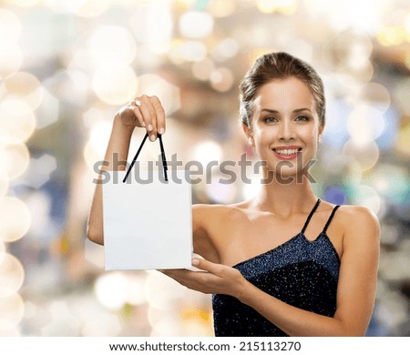 luxury, advertisement, holydays and sale concept - smiling woman with white blank shopping bag over lights background