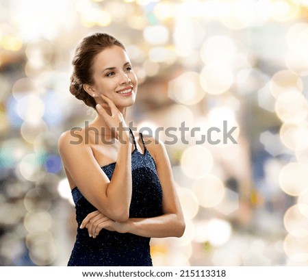 people, holidays and glamour concept - smiling woman in evening dress over black background over lights background