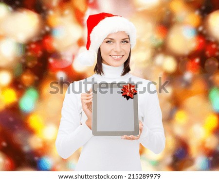 christmas, technology, present and people concept - smiling woman in santa helper hat with blank screen tablet pc computer over red lights background